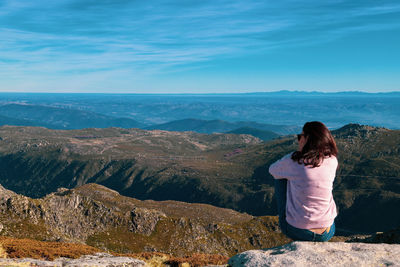 Rear view of woman looking at mountains against sky