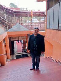 Full length portrait of young man standing against built structure