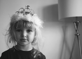 Portrait of cute girl wearing crown while standing against wall