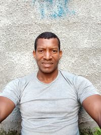 Portrait of smiling young man standing against wall