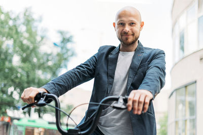 Portrait of man holding bicycle standing outdoors