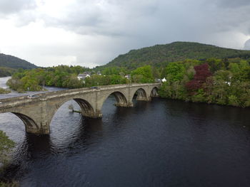 Arch bridge over river against sky