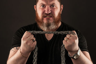 Portrait of man holding camera against black background