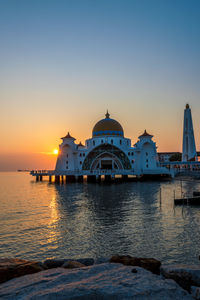 View of sea and buildings against sky during sunset