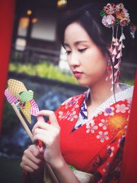 Close-up of young woman holding red flowers