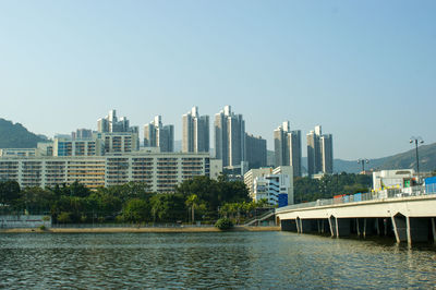 Bridge over river against buildings in city against clear sky