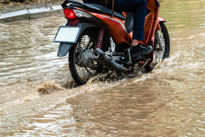 Man ride motorcycle passing through flooded road. riding motorbike on flooded road during flood 