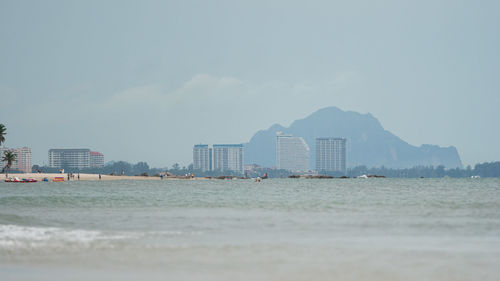 Sea and buildings in city against sky