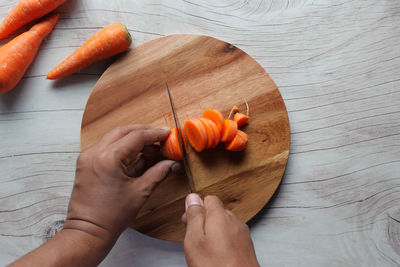 Top view of man hand cutting carrot on chopping board