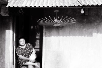 Portrait of young woman standing against building