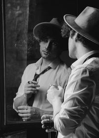 Man wearing hat looking in mirror at home