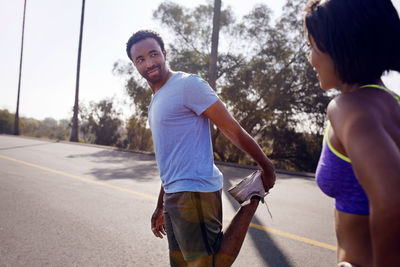 Man looking at woman while stretching on street