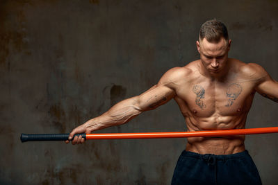 Determined athlete holding stick against black wall