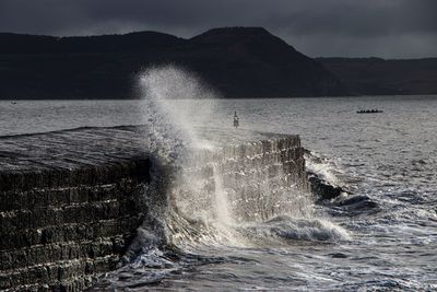 Sea waves splashing on rocks against sky on the cobb at lyme regis