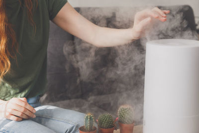 Midsection of woman sitting by humidifier