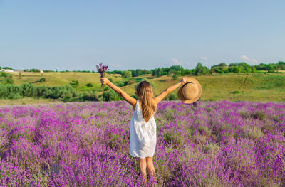 Rear view of girl holding hat with arms outstretched at farm