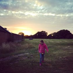 Man standing on grass against cloudy sky