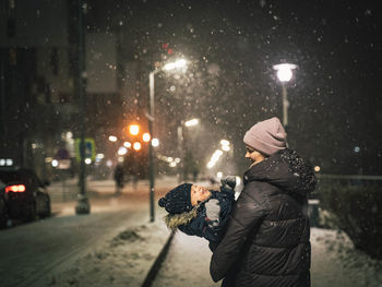 Rear view of woman standing on street at night