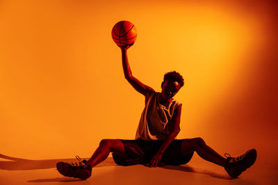 Man playing with ball against sky during sunset