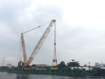 Cranes at commercial dock against sky