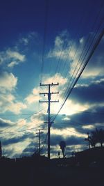 Low angle view of electricity pylon against cloudy sky