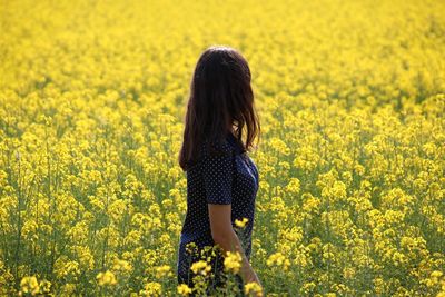 Rear view of woman with yellow flowers in field