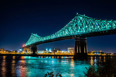 Illuminated bridge over river at night