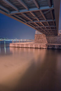 Illuminated bridge over river against sky