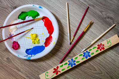 High angle view of paintbrushes with watercolor paints on wooden table
