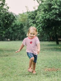 Full length of cute girl running on grassy field in park