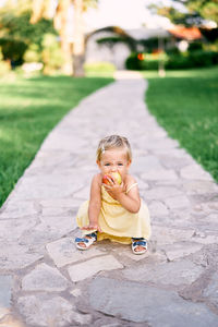 Portrait of boy sitting on footpath