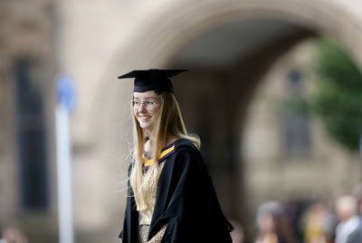 Portrait of woman wearing graduation gown standing outdoors