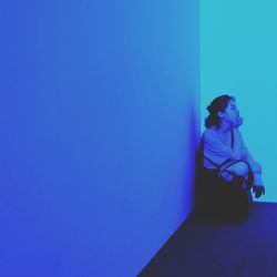 Woman sitting against blue wall
