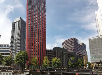 Low angle view of skyscrapers against cloudy sky