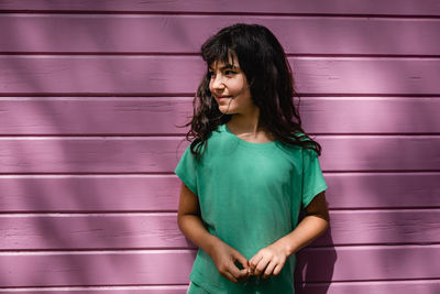 Portrait of smiling girl standing against bright pink wall