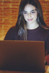 Portrait of young woman using laptop at home