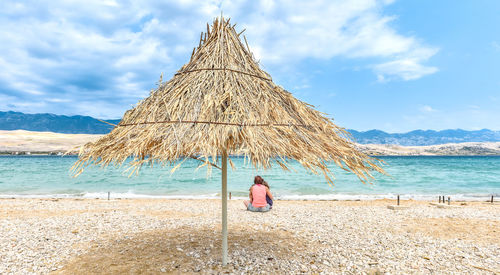 Mother with children seen through thatched roof parasol on shore at beach