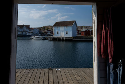 Sailboats moored on sea by buildings against sky in city