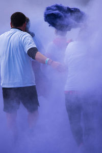 People walking amidst purple powder paint during holi