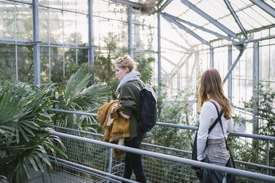 Women walking amidst plants in greenhouse