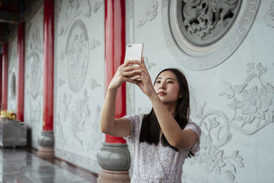 Young woman looking at camera while using phone