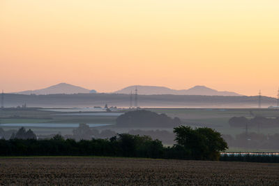 Scenic view of agricultural field against sky during sunset