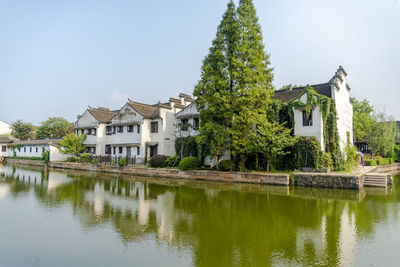 Houses by lake and buildings against sky