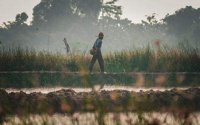 Rear view of woman walking on field