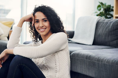 Portrait of smiling young woman sitting on sofa