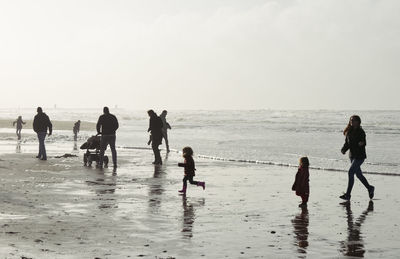 People walking on beach against sky