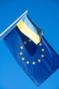 The eu flag together with a ucrainian flag in front of a blue sky