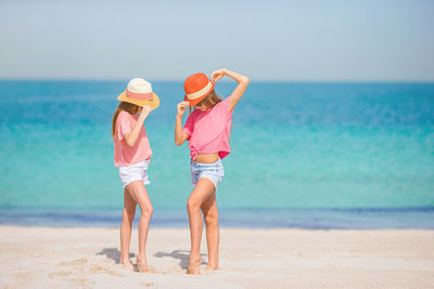 Full length of girls wearing hat standing on beach