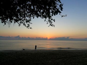 Silhouette people on beach against sky during sunset