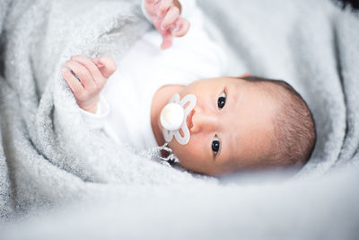 Close-up portrait of cute baby boy lying on bed